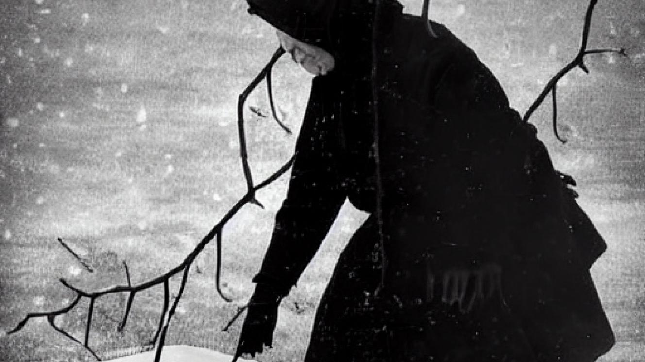 A woman picking up a basket in a snowy winter