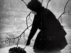A woman picking up a basket in a snowy winter